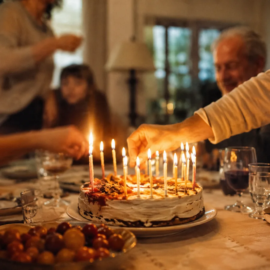 Un gâteau d'anniversaire aux bougies allumées sur une table de famille